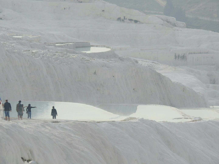 沿着湖边雪地上的小山丘走的人们