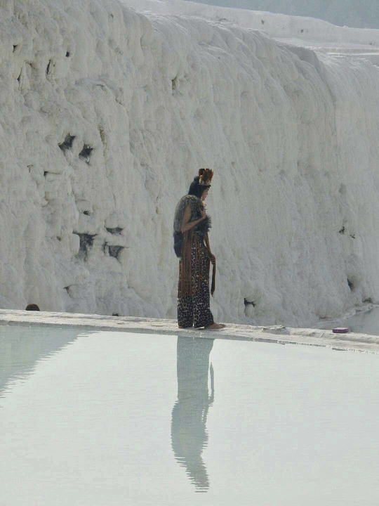 一个人和一个女人站在雪墙前 背景有一个水池和一个瀑布。