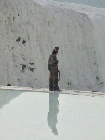 一个人和一个女人站在雪墙前 背景有一个水池和一个瀑布。