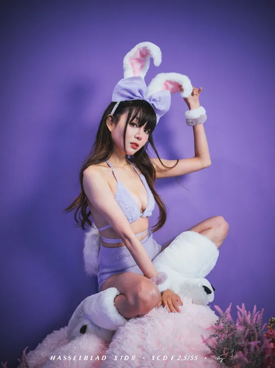 一位穿着紫色裙子和帽子 抱着一只白色兔子的年轻女子