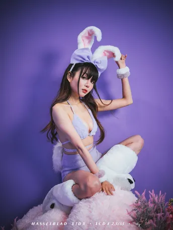 一位穿着紫色裙子和帽子 抱着一只白色兔子的年轻女子