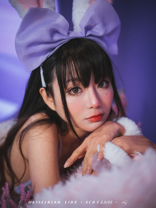 一个年轻女子抱着一只带紫色耳朵的兔子