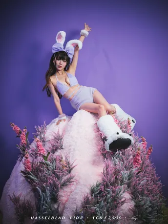 一个穿着白色连衣裙的女人坐在粉红色毛绒玩具上
