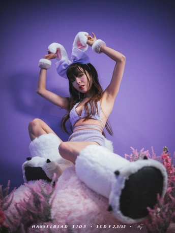一个年轻女子坐在一只白色毛绒玩具上。