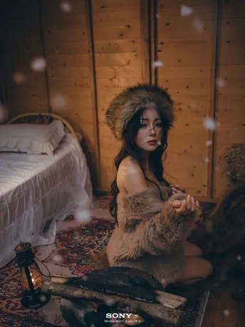 一个穿着皮大衣的女孩坐在一个带有床和灯笼的房间里
