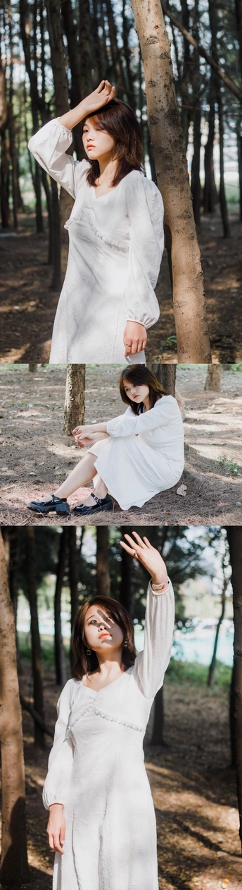 一个穿着白色连衣裙的女人站在一片树林里