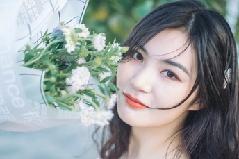 一位年轻女子撑着一把脸上开着白花的伞的肖像