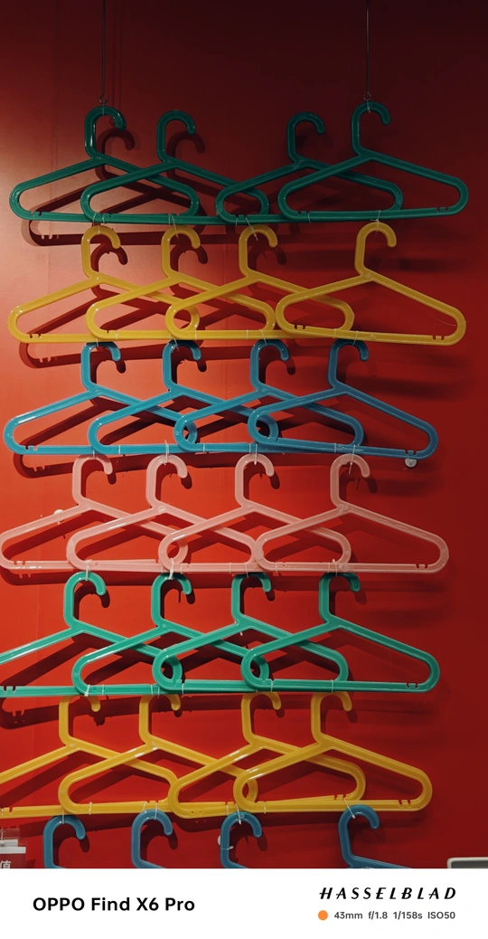 多彩衣架悬挂在红色墙壁上的钩子上