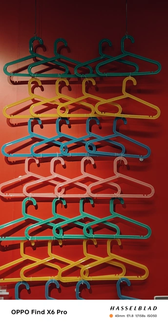 多彩衣架悬挂在红色墙壁上的钩子上