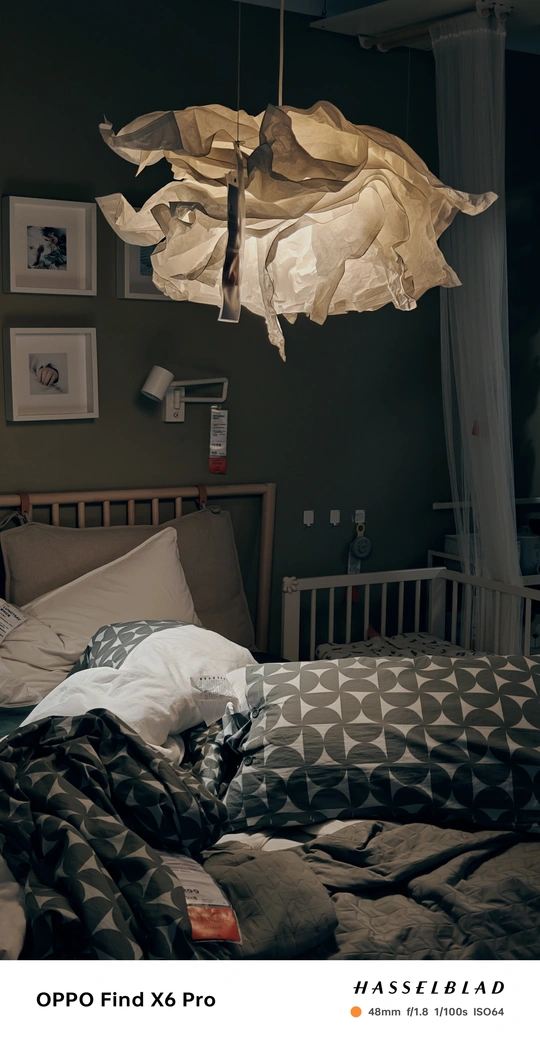 一个黑暗的卧室 墙上挂着画 床上的床单从天花板垂下。