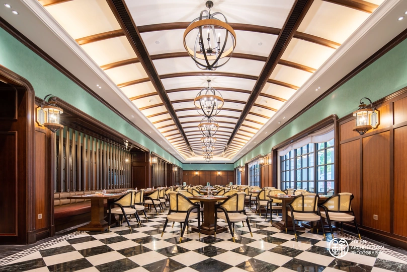 一个带有黑色和白色棋盘式地板的大型餐厅 天花板上有吊灯。