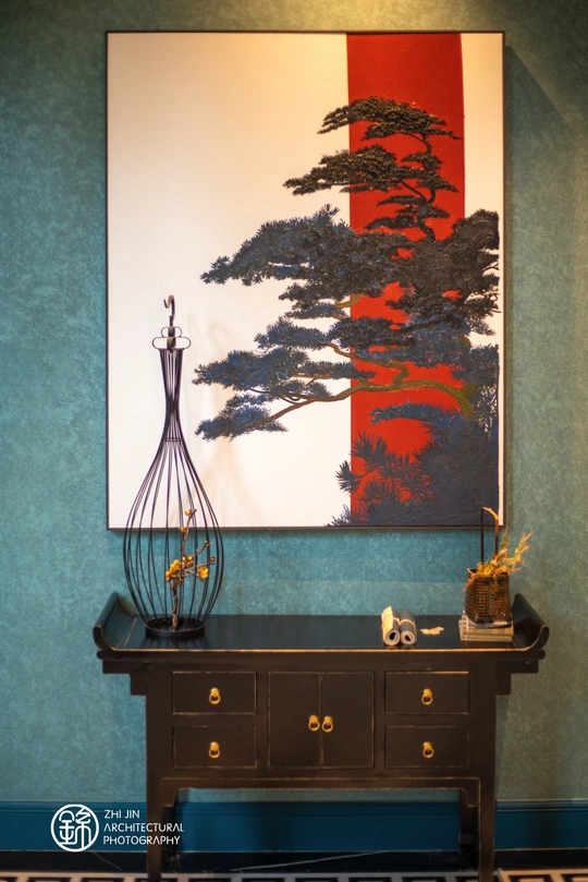 一个带有蓝色墙壁的房间 桌子上放着一幅插在花瓶里的树的画。