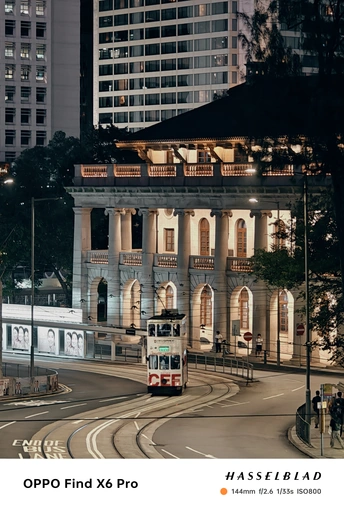 夜间行驶在高层建筑旁边街道的一辆公交车