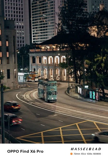 夜间行驶在城市街道上的绿色双层公交车 背景是高楼大厦 以及路上行驶的蓝色公交车。