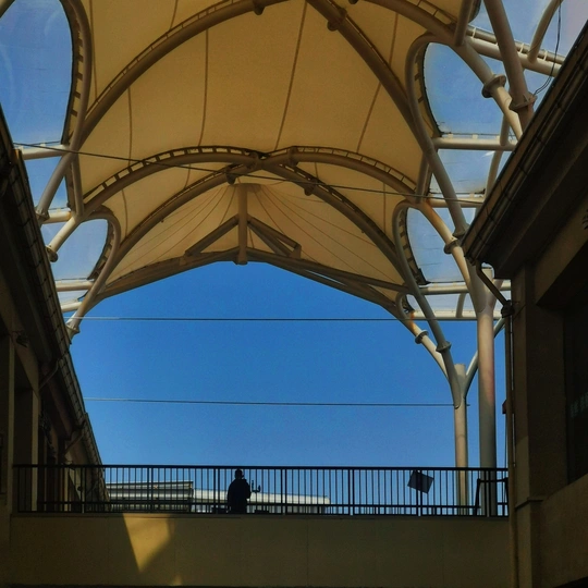 人们在蓝色的天空中在建筑物的屋顶下走动。