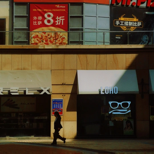 一个人走过一家商店和餐厅前面的街道。