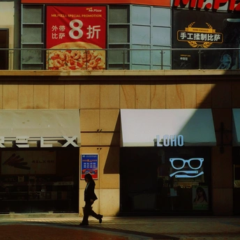 一个人走过一家商店和餐厅前面的街道。