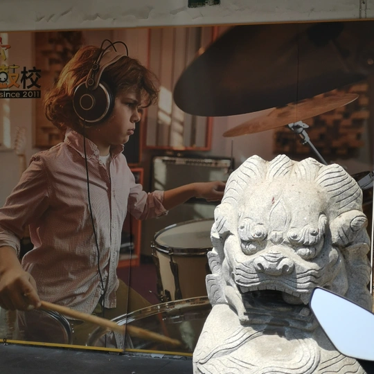 一位戴着耳机敲鼓的女性站在一头狮子雕像旁边