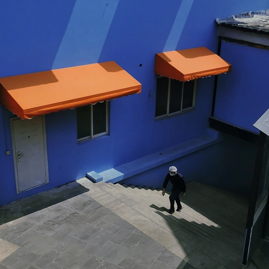 一个人走进了蓝色建筑的庭院