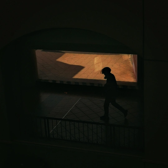 夜晚的黑暗街道上 一个人影在窗户旁边经过。