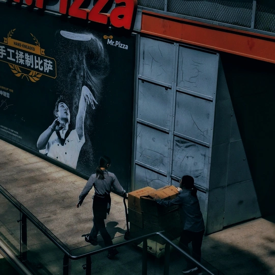 一个推着行李箱的男人沿着自动扶梯走 同时有一对夫妇经过。