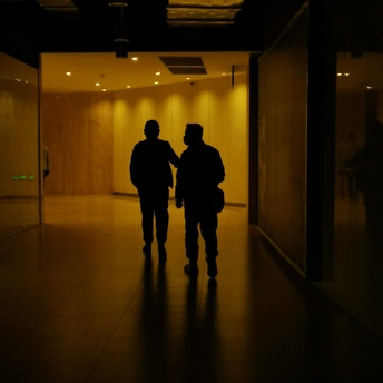 一个人和一个女人在夜晚的办公楼里走下黑暗的走廊 手牵着手。