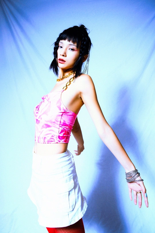 一位穿着白色上衣和粉色裙子的年轻女子 伸展着她的手臂站立着。