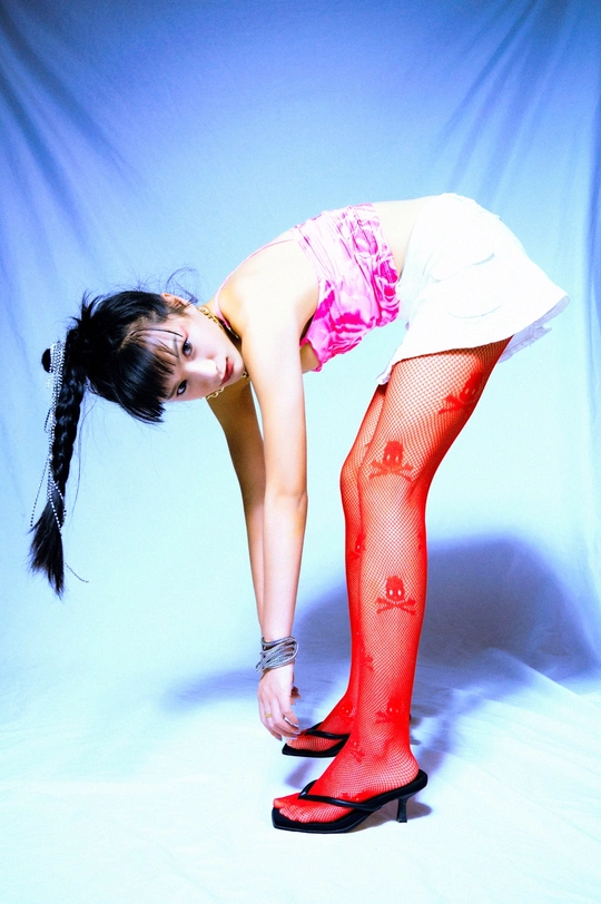 一位穿着红色紧身裤和高跟鞋的年轻女子在蓝色背景前摆姿势