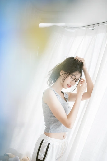 一个戴眼镜的年轻女子站在窗前梳头