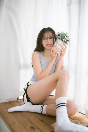 一个穿着白袜子拿着杯子坐在窗户旁边的年轻女人