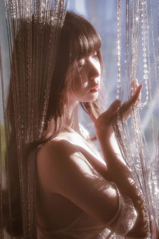 一位年轻女子站在窗前 窗帘是透明的。