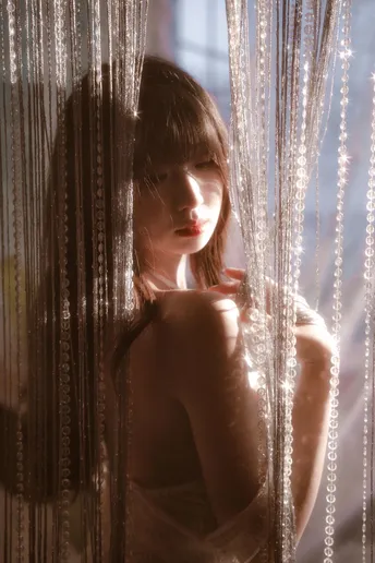 一位穿着连衣裙的年轻女子站在窗前