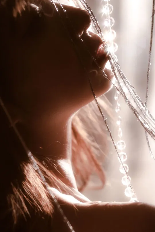 一位年轻女子 头发被阳光透过窗户照射 形成背光效果。