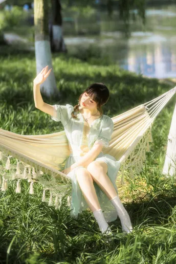 一个女孩穿着仙女装坐在草地上的一把吊床上