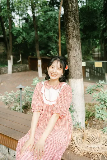 一位穿着粉红色连衣裙的年轻女子站在木凳上