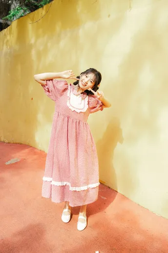 一个小女孩穿着粉红色裙子站在黄色墙壁前