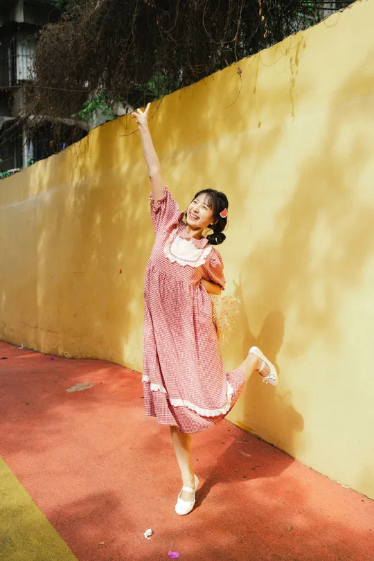 一个小女孩穿着粉红色裙子在对着黄色墙壁跳舞