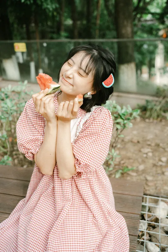 一个小女孩穿着粉色裙子在吃西瓜。