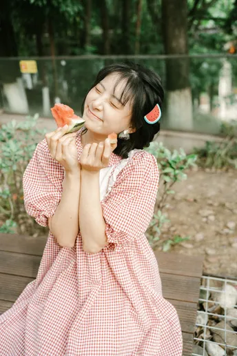 一个小女孩穿着粉色裙子在吃西瓜。