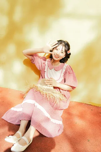 一位穿着粉红色和白色连衣裙的年轻女子拿着竹棍