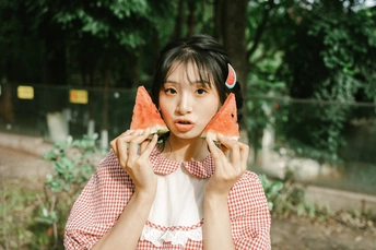 一位年轻女子举着一个西瓜贴着她的脸