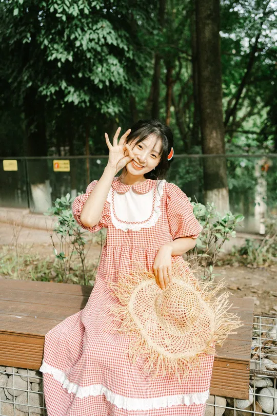 一个小女孩穿着粉红色裙子站在外面