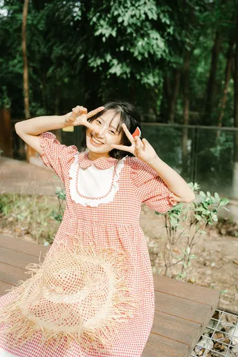 一个穿粉色连衣裙的年轻女子用手做表情