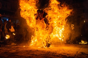 一个人站在街边 旁边有一个大型篝火 他身上燃起了火焰。