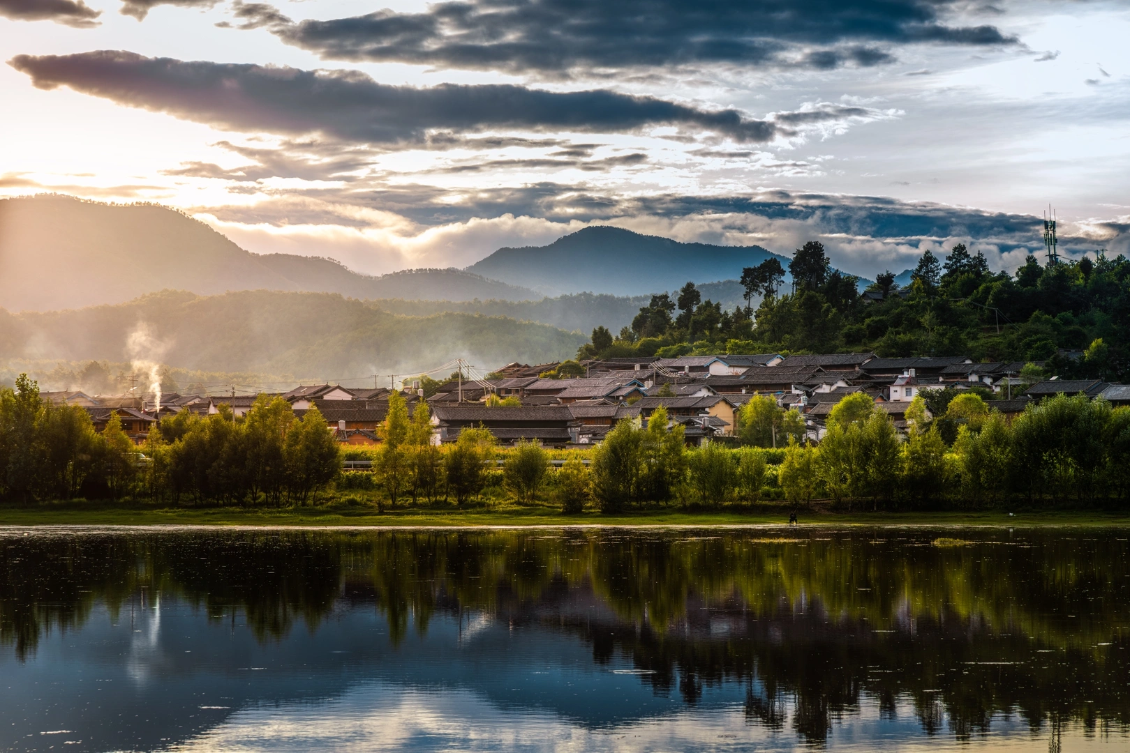 一个小城镇或村庄在河上的日落 背景是山脉