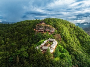 一片被森林环绕的绿色山丘上的寺庙 aerial view