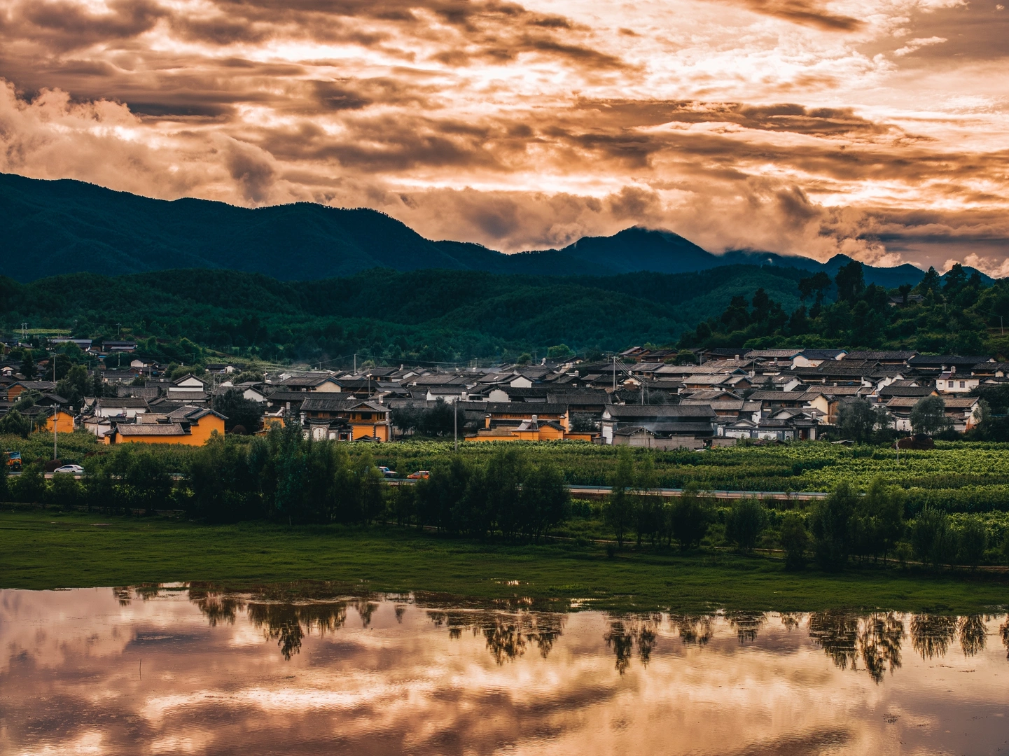 夕阳下的小镇或村庄 山谷中有山脉 天空中云朵飘过。