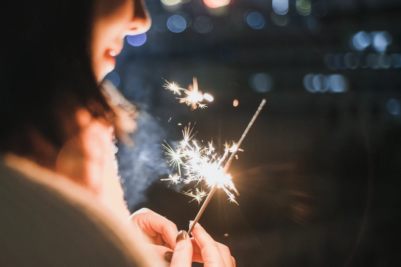 一个小女孩在晚上手里拿着一个点燃的火花