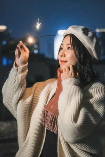 夜晚屋顶上的一个年轻女子手持点燃的火花