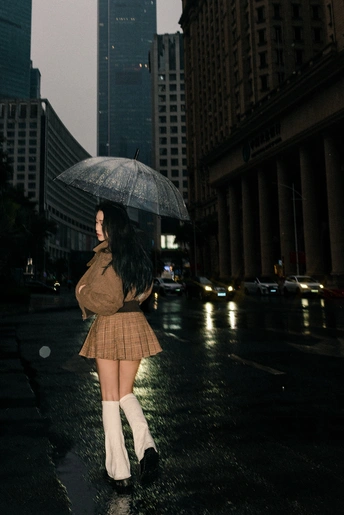 一位年轻女子在雨夜的城市街道上打着伞走下街道